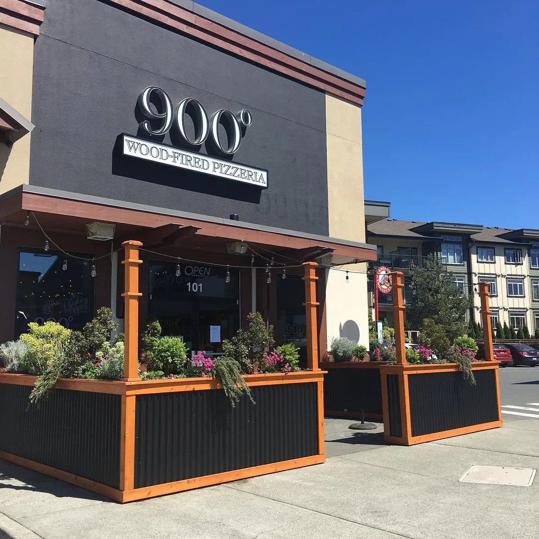 The 900° Wood-Fired Pizzeria storefront in Langford on a sunny day, with its patio planters and orange trim.