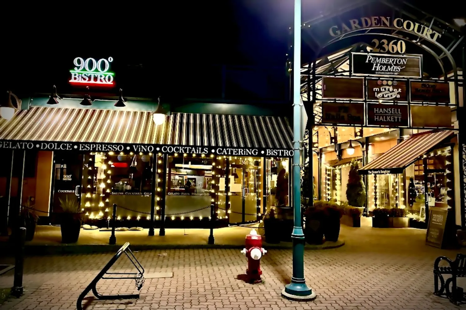 The 900° Bistro sign glowing above the striped awnings of the Garden Court arcade in Sidney at night.